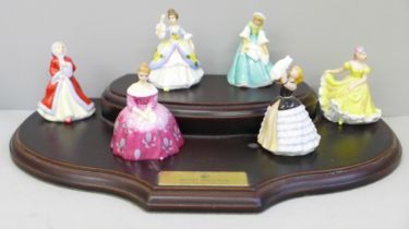 Six miniature Royal Doulton ladies, boxed, with a wooden display stand