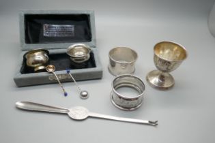 A silver lobster pick, two silver napkin rings, a weighted silver egg cup and two salts with spoons,