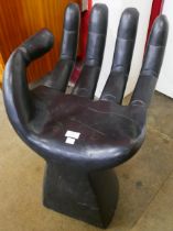 An ebonised hand shaped stool