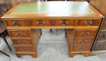 A yew wood and green leather topped pedestal desk