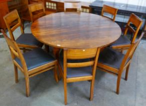 A large teak and afromosia circular dining table and eight chairs