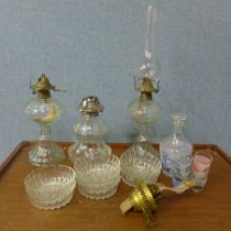 Three glass oil lamps, a set of glass dishes, a decanter and shot glass set