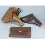 Two leather pistol cases/holsters and a leather cartridge case