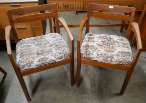 A pair of teak elbow chairs
