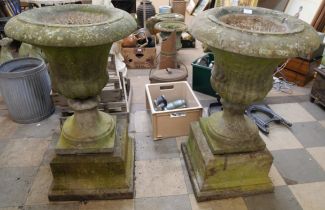 A pair of large concrete campana shaped garden urns on stands