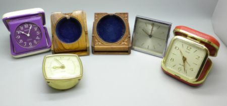 Two carved wood watch holders and vintage travel clocks