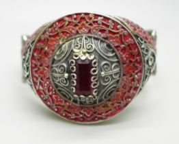 A white metal bangle set with a red stone, French control marks, circular detail 42mm in diameter