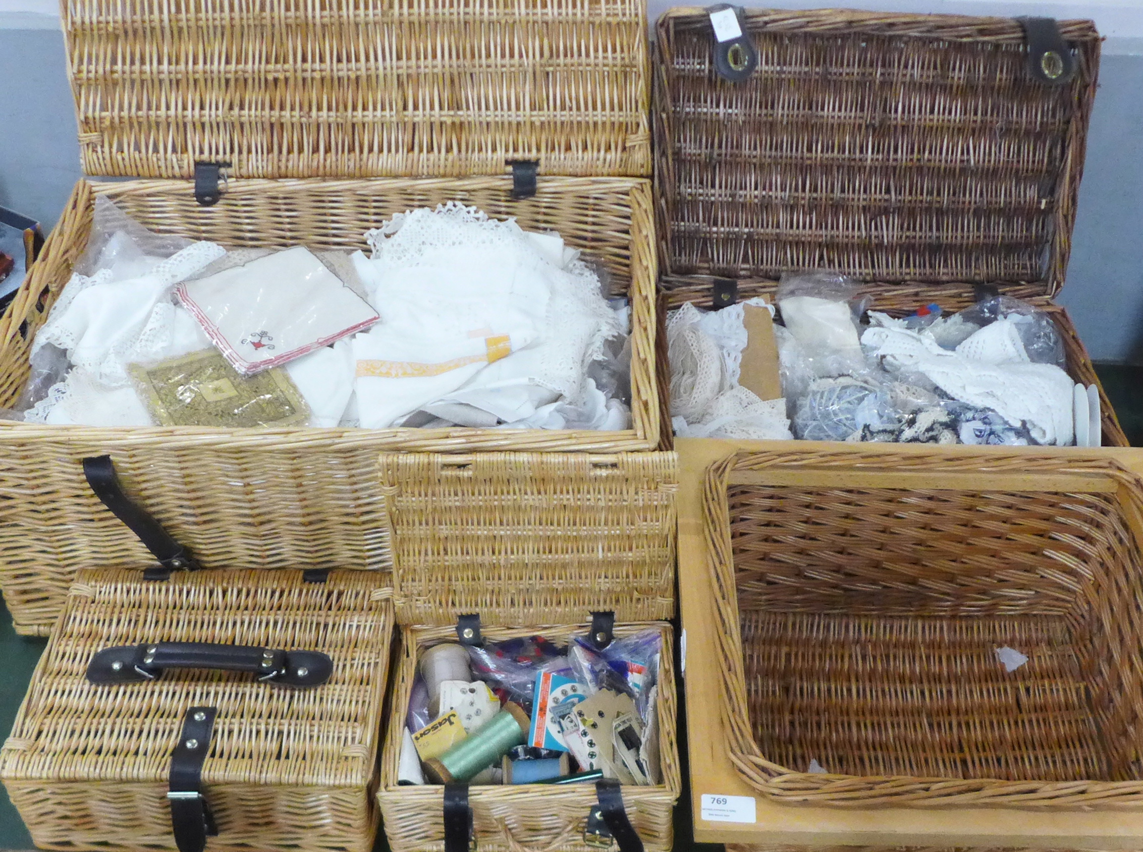 Four wicker baskets, one containing linen, one trims, lace and crochet edge, one haberdashery and