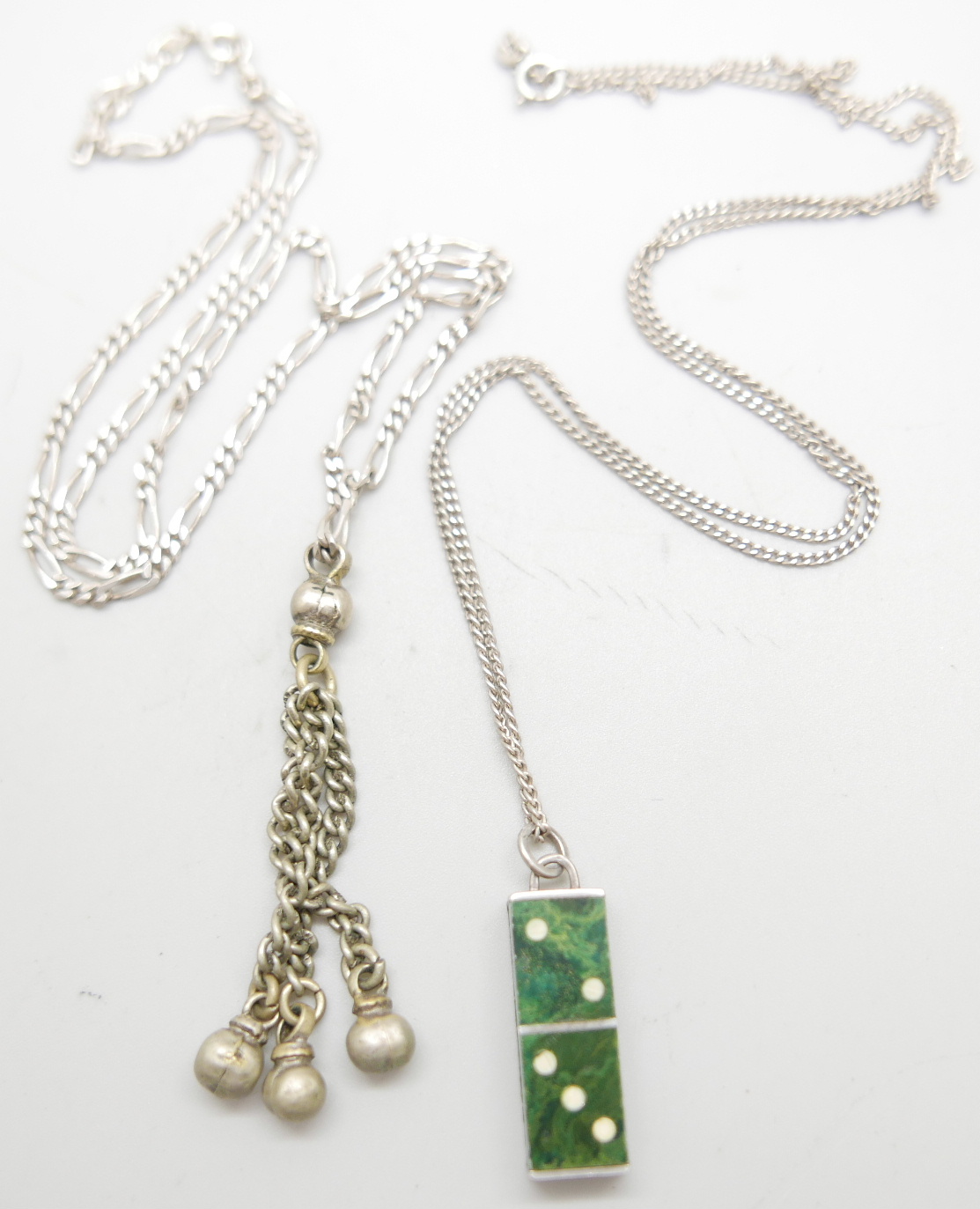 Two silver chains, a silver domino pendant and one other pendant