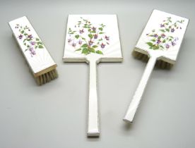 A silver and enamelled hand mirror and two brushes, Birmingham 1950