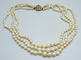A three strand pearl necklace with a ruby and diamond clasp