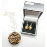 A carved silver mounted tigers eye pendant on a silver chain and a pair of tigers eye earrings,