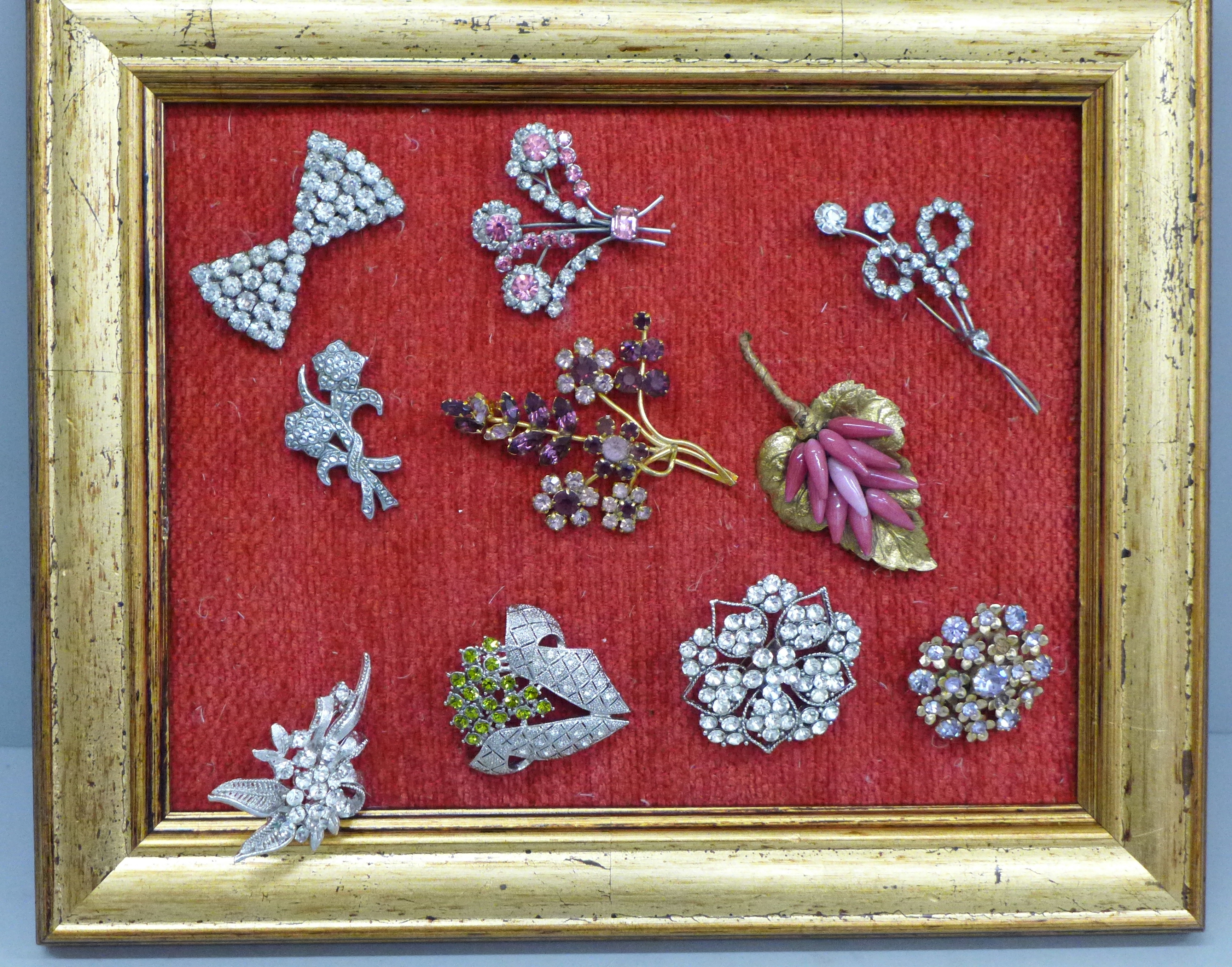 Ten vintage costume brooches on a display stand