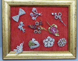 Ten vintage costume brooches on a display stand