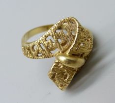 A yellow metal ring, (tests as 18ct gold, hallmark worn), with stylised cross over ribbon of gold
