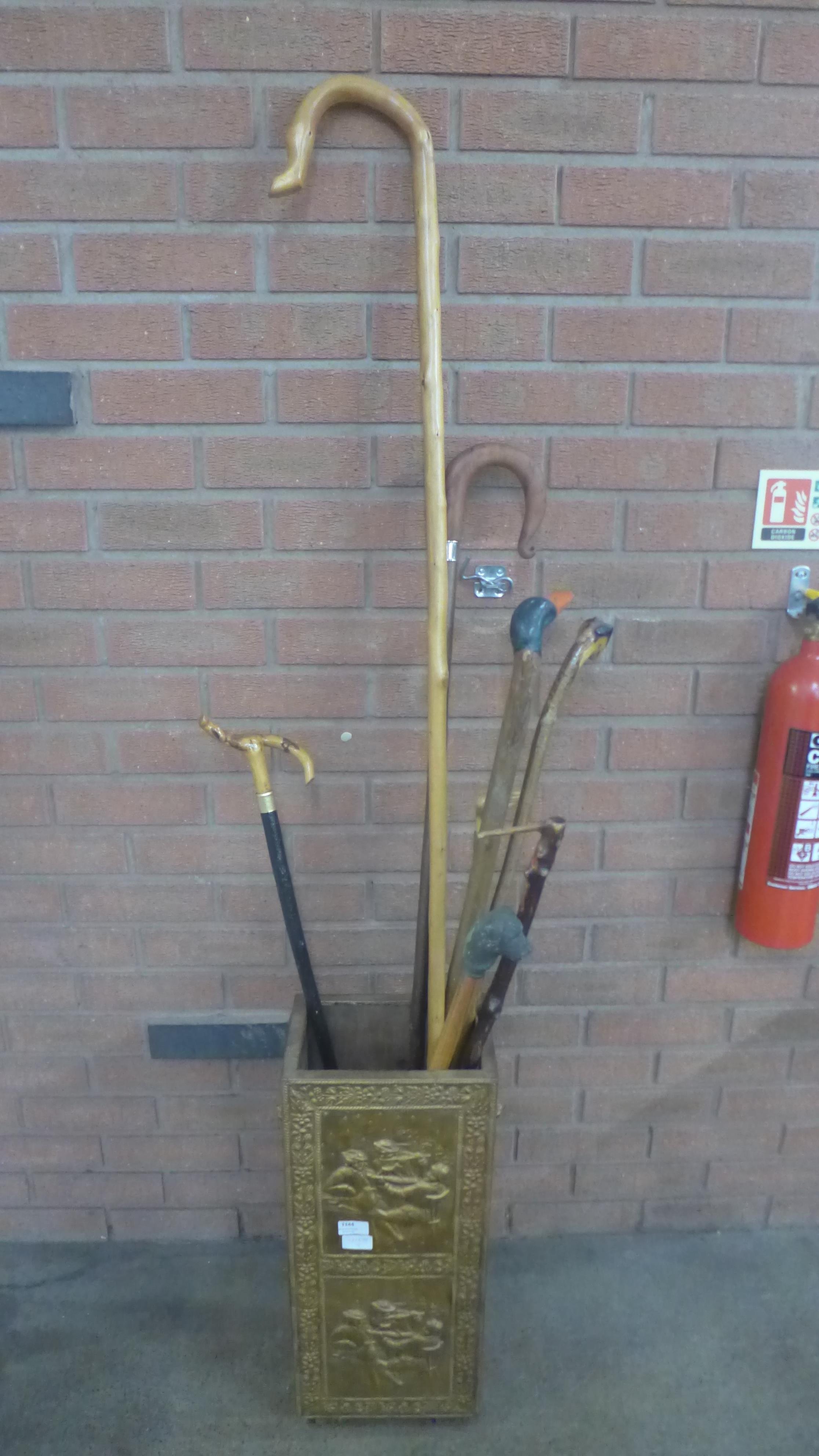 A brass covered stick stand with seven walking sticks and a crook **PLEASE NOTE THIS LOT IS NOT