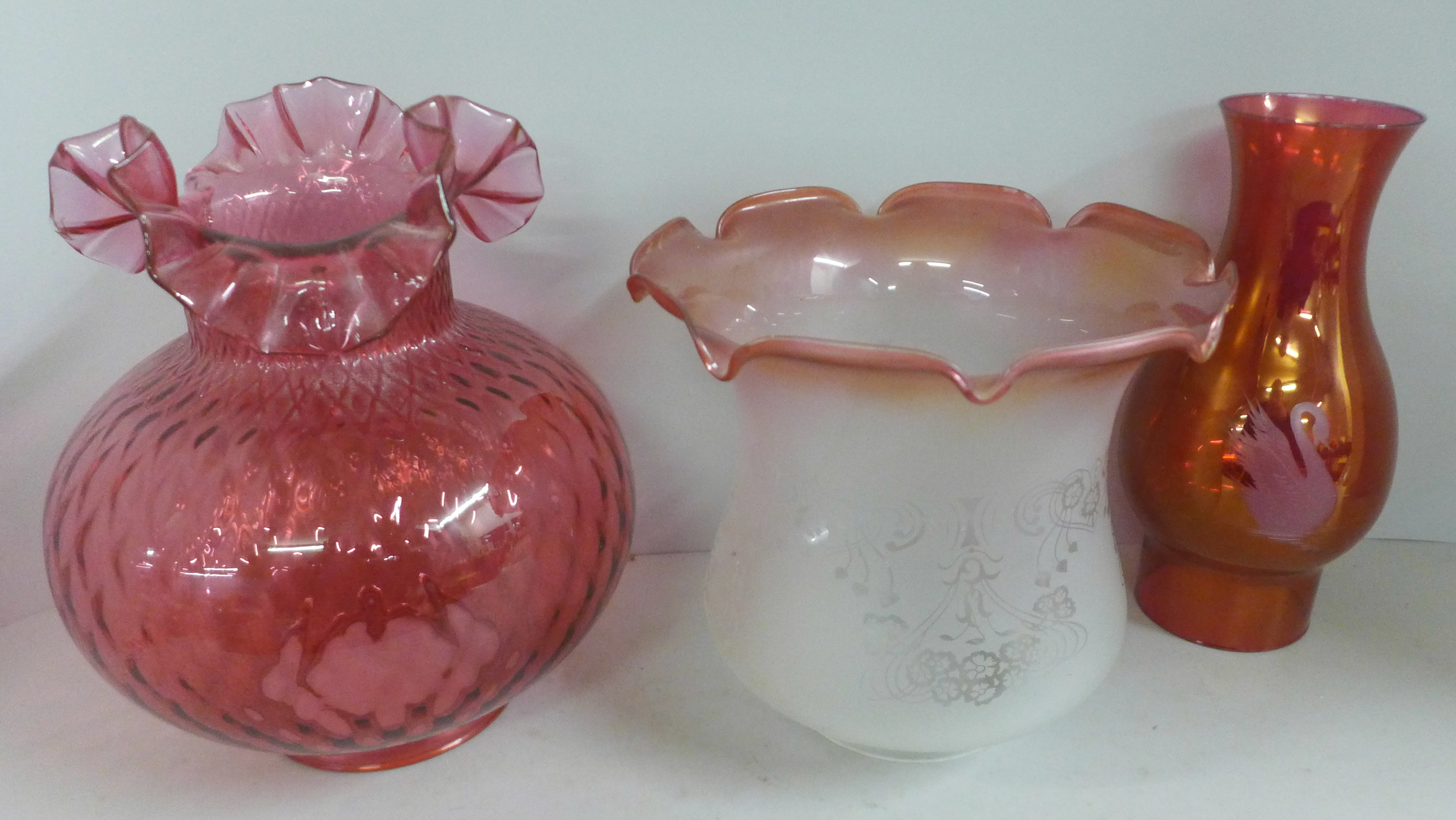 A cranberry glass oil lampshade, one other etched glass shade and an etched pink glass shade