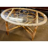 An oval bamboo and glass topped coffee table