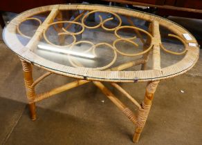 An oval bamboo and glass topped coffee table
