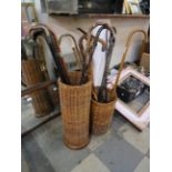 A wicker stick stand with eight walking sticks (seven with silver collars/embellishments) and an