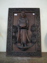 An oak carved wall plaque, depicting a monk