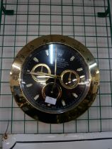 A gold coloured Rolex style dealers display wall clock