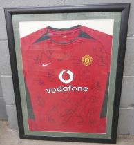 A framed Manchester United football shirt with the team's autographs