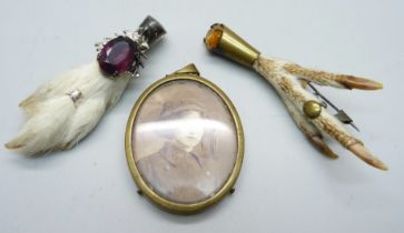 A c1900 photograph in a brass cased pendant, two lucky brooches; a rabbit's foot with gem detail and