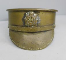 A WWI trench art shell made into an officer's cap with applied RASC badge, shell base dated 1914