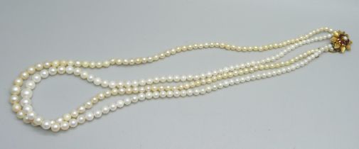 A two row pearl necklace with 9ct gold and garnet clasp, (three row clasp)
