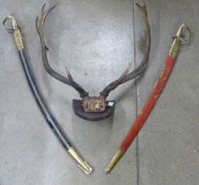 A set of mounted antlers and two Indian swords