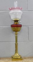 An Art Nouveau brass oil lamp with ruby glass reservoir