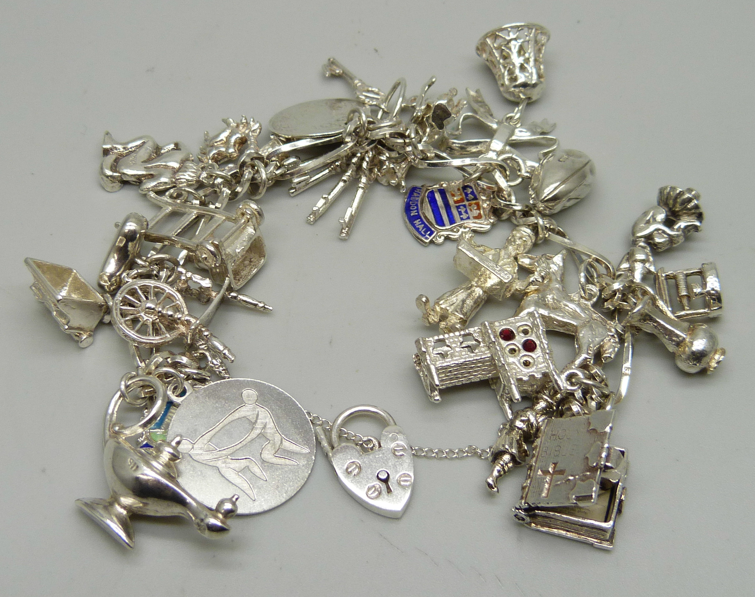 A silver charm bracelet with 26 charms, 63.9g