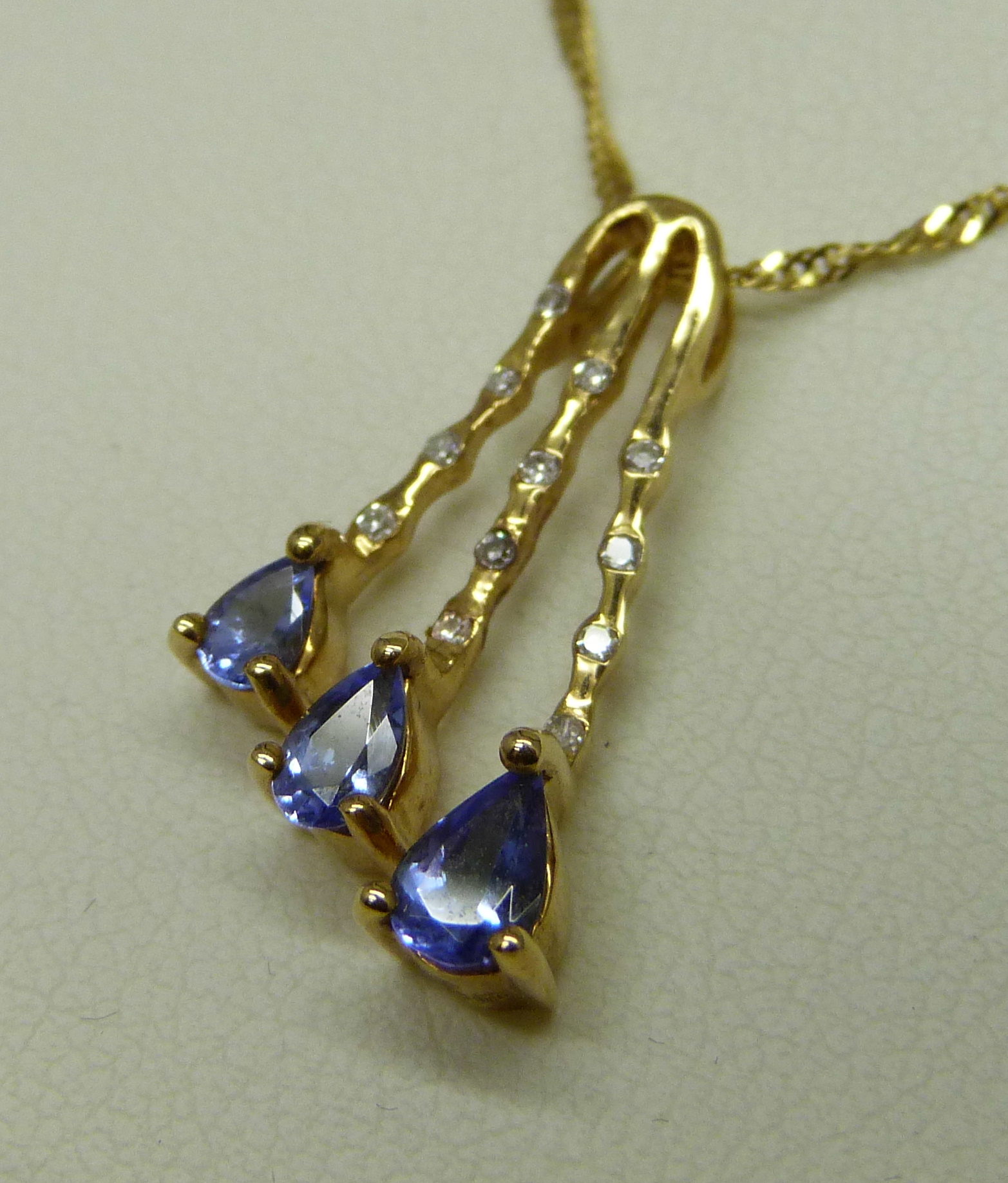 An 18ct yellow gold pendant set with small diamonds and three pear shape grade AAA tanzanite stones, - Image 3 of 6