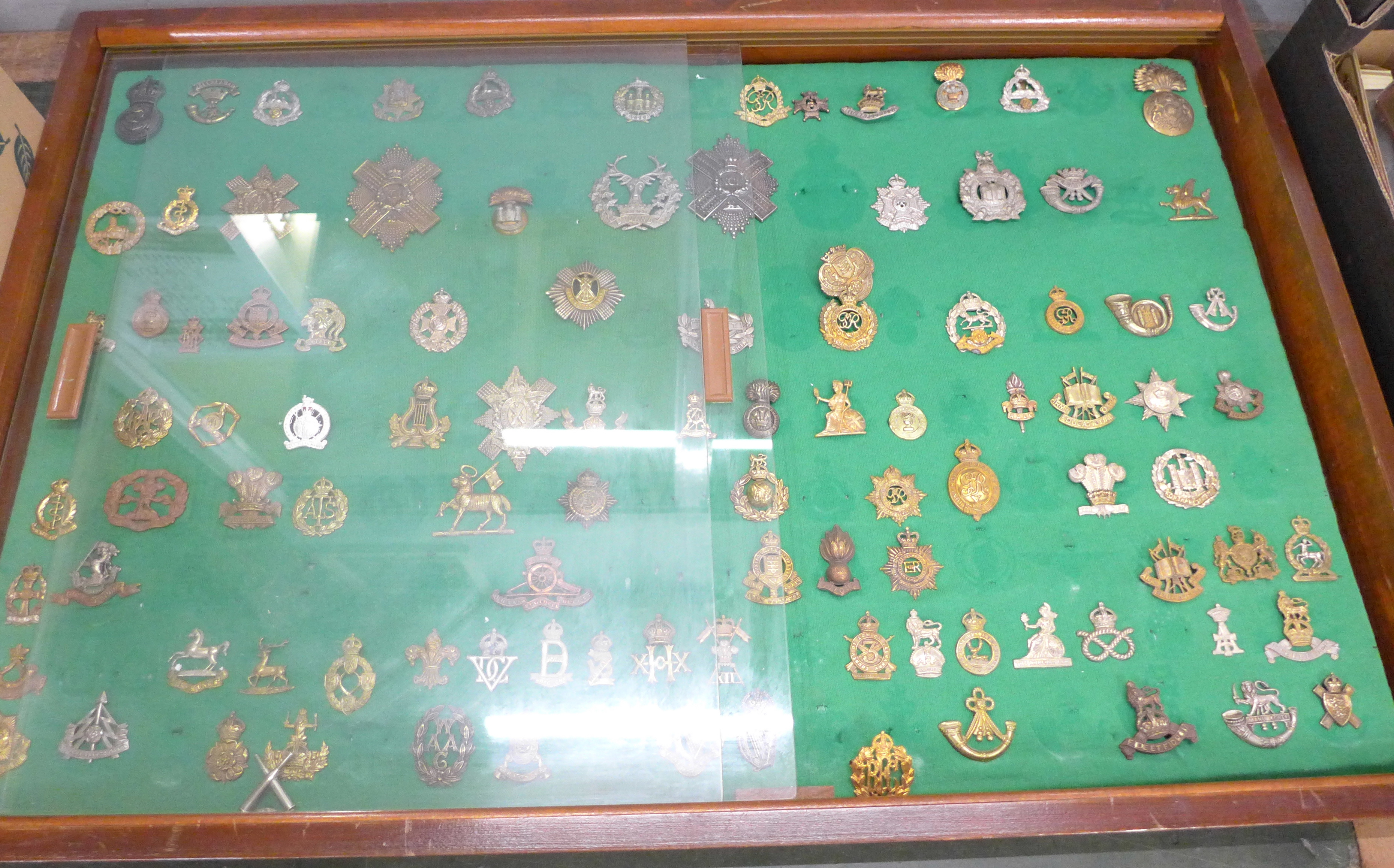 A large collection of military cap badges including Gordon Highlanders, Scottish Light, Royal