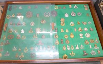 A large collection of military cap badges including Gordon Highlanders, Scottish Light, Royal