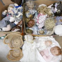 A collection of porcelain costume dolls, two wicker doll's chairs and a realistic baby doll with bed