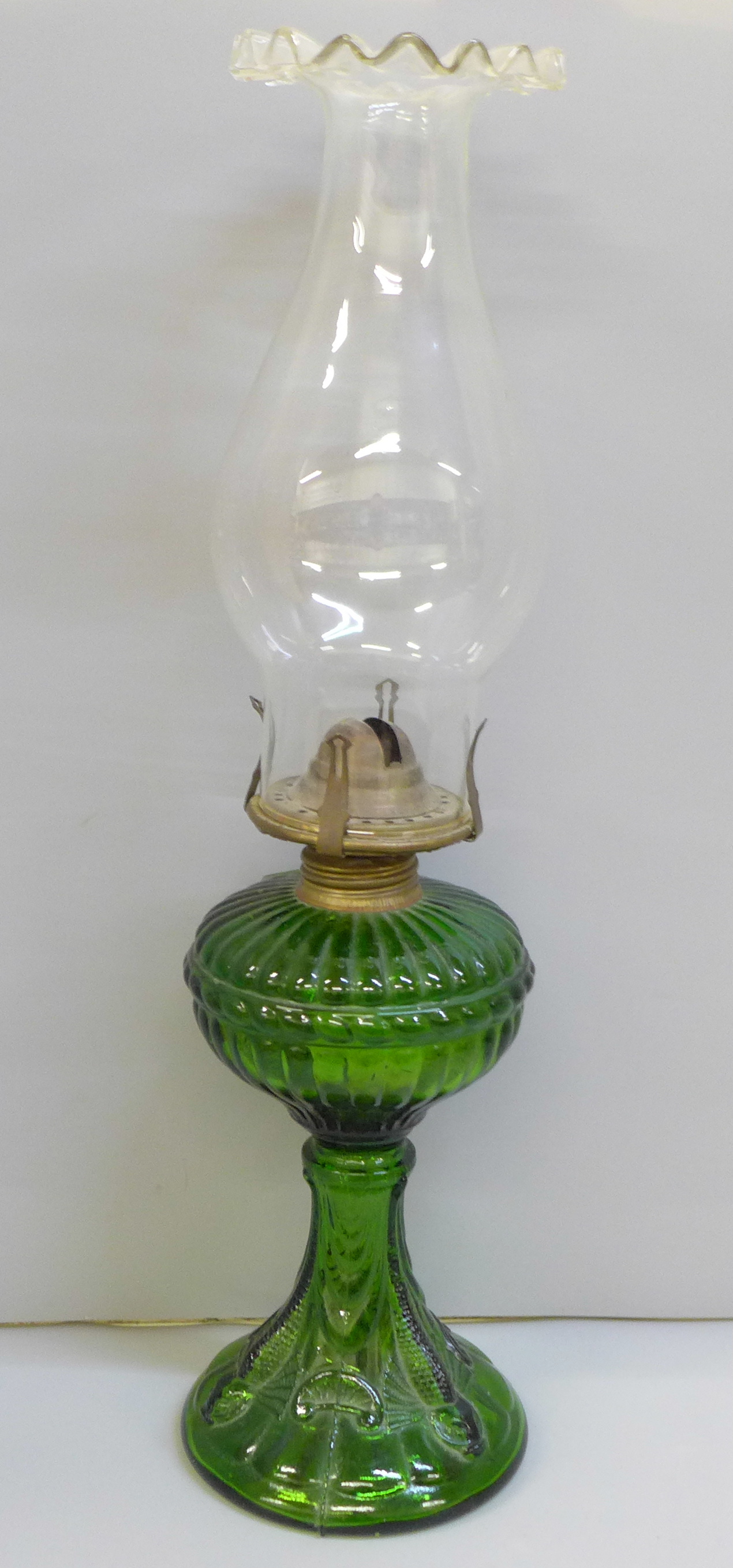 An oil lamp, green glass base with fish detail and original glass chimney