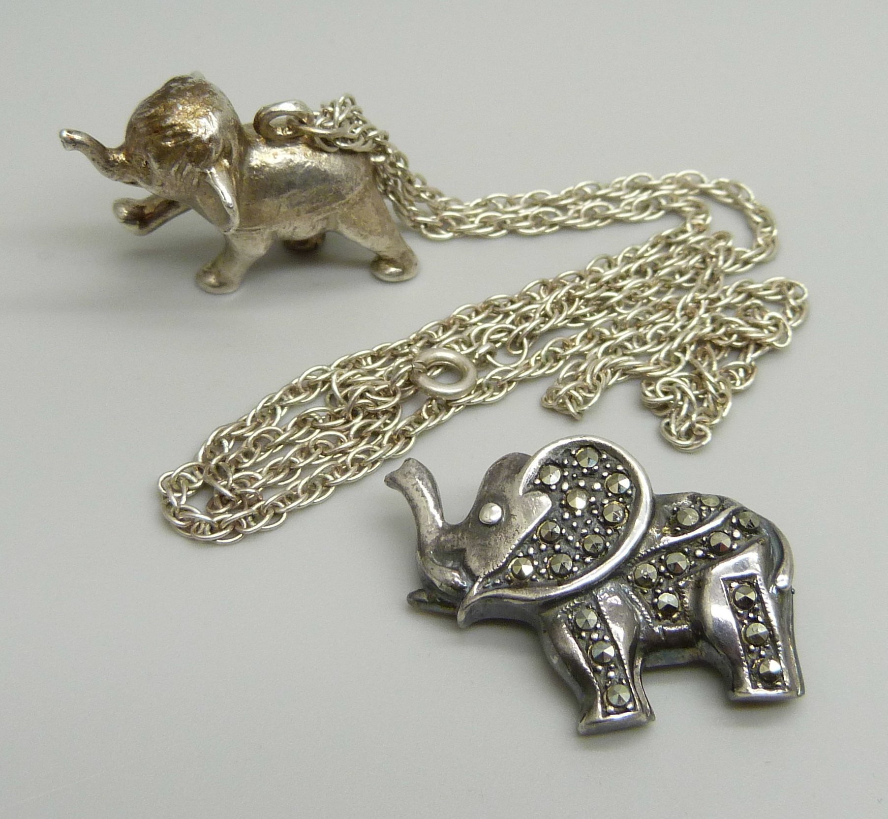 A hallmarked silver Dumbo pendant on a silver chain and a silver and marcasite elephant brooch