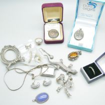 A collection of silver jewellery including a locket, brooches and a ring