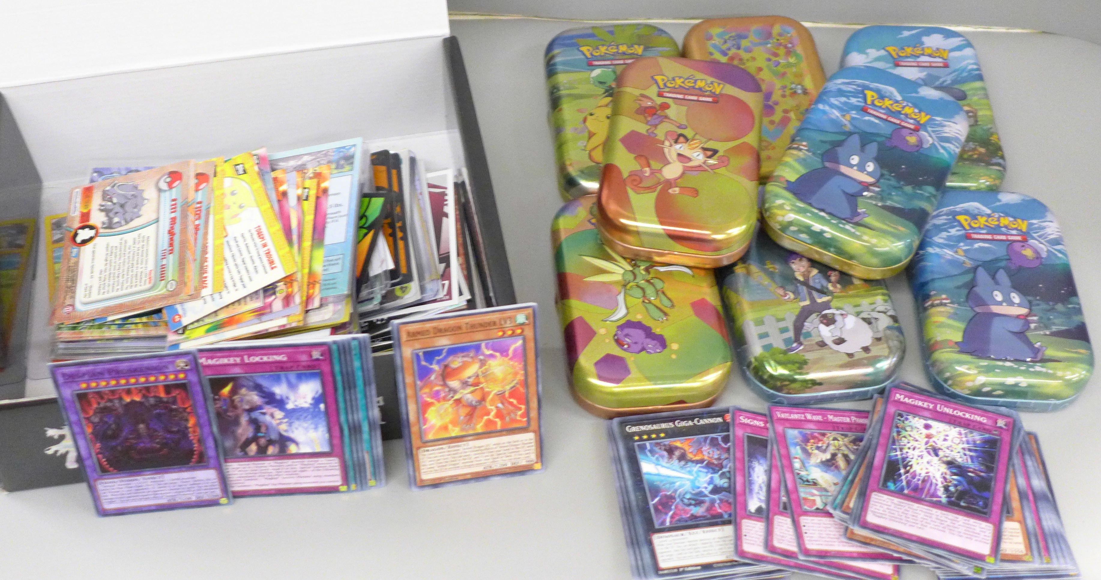 Eight Pokemon tins, Yu-gi-Oh! gaming cards and a mix of gaming cards