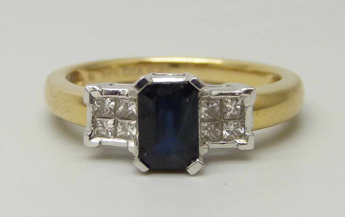 An 18ct yellow gold ring set with a central sapphire (6 x 4mm) and four princess cut diamond on each