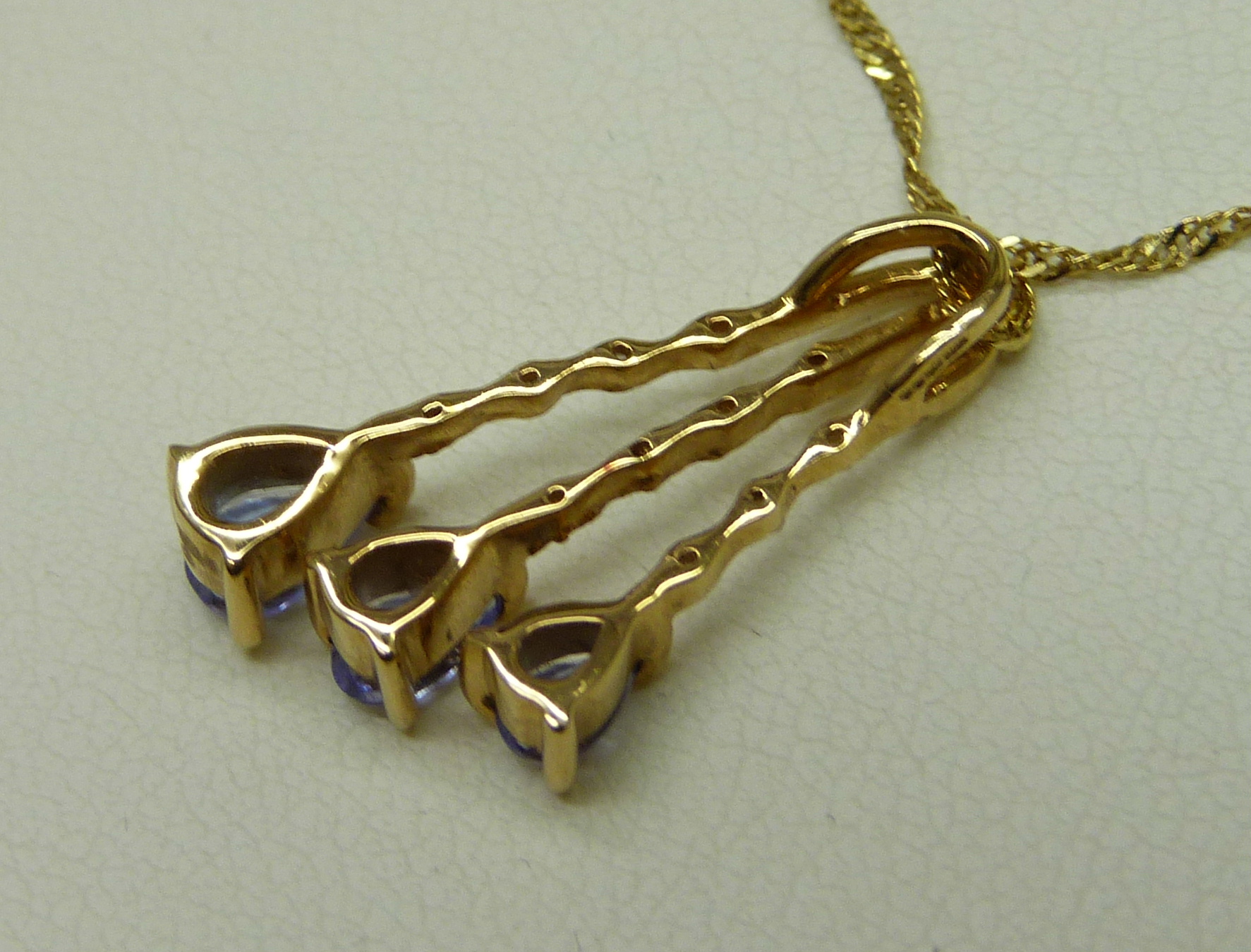 An 18ct yellow gold pendant set with small diamonds and three pear shape grade AAA tanzanite stones, - Image 4 of 6