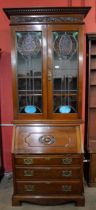 An Art Nouveau carved walnut and stained glass bureau bookcase