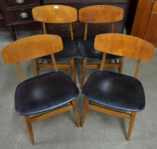 A set of four teak and black vinyl chairs