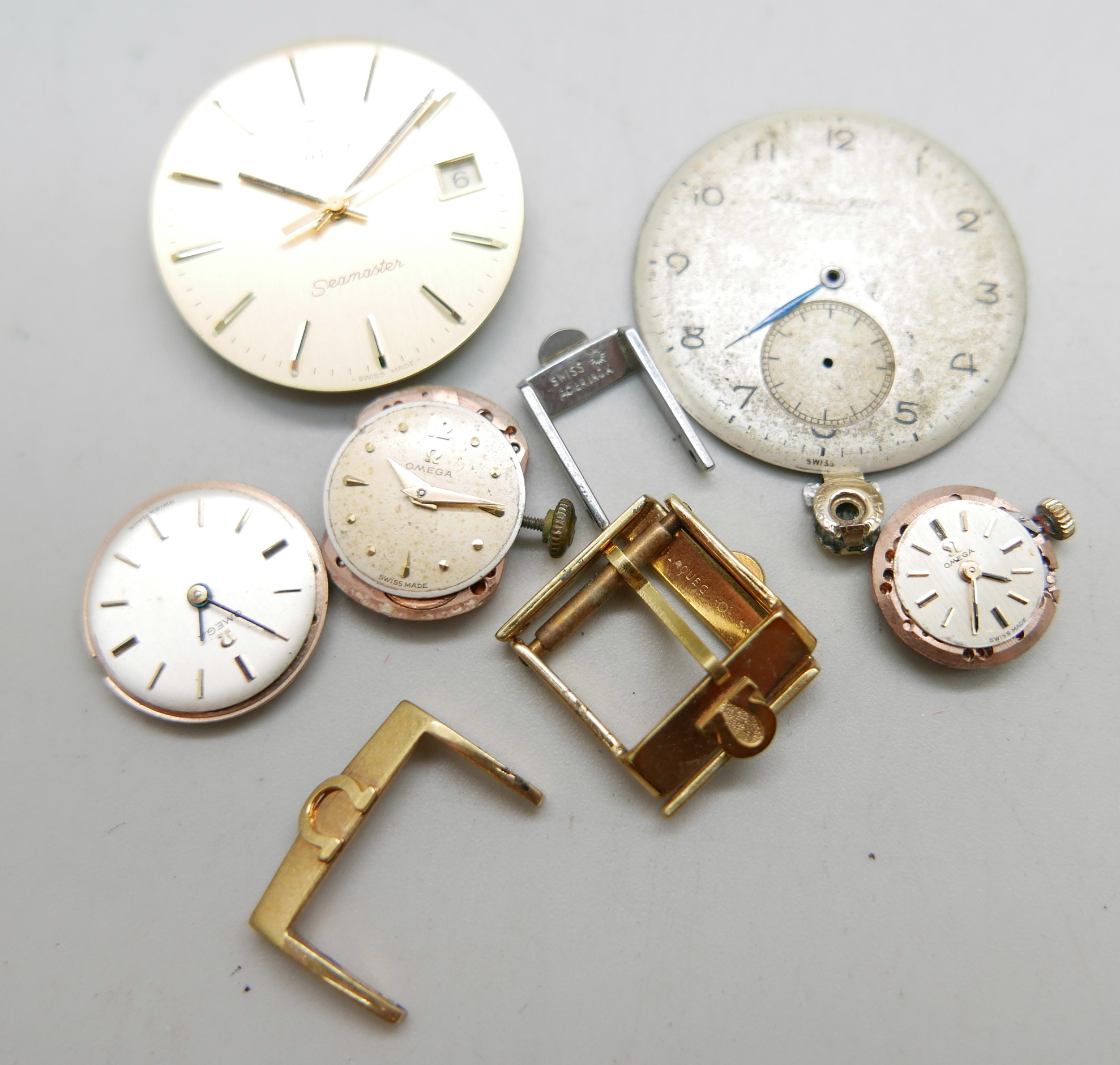 Four Omega strap buckles, an International Watch Company watch dial, three lady's Omega watch