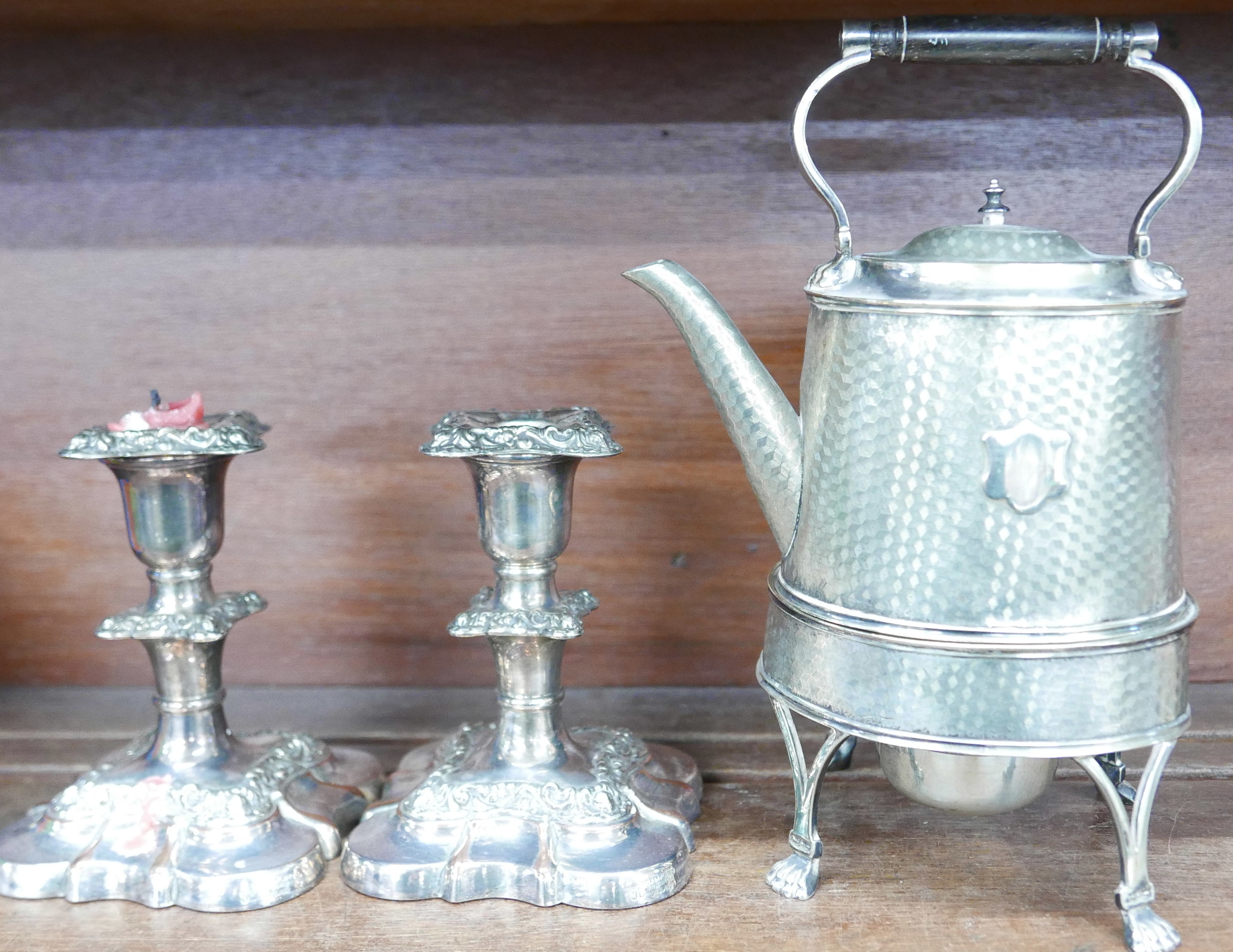 A silver plate coffee pot on stand, on paw feet and crest plate and a pair of plated candlesticks