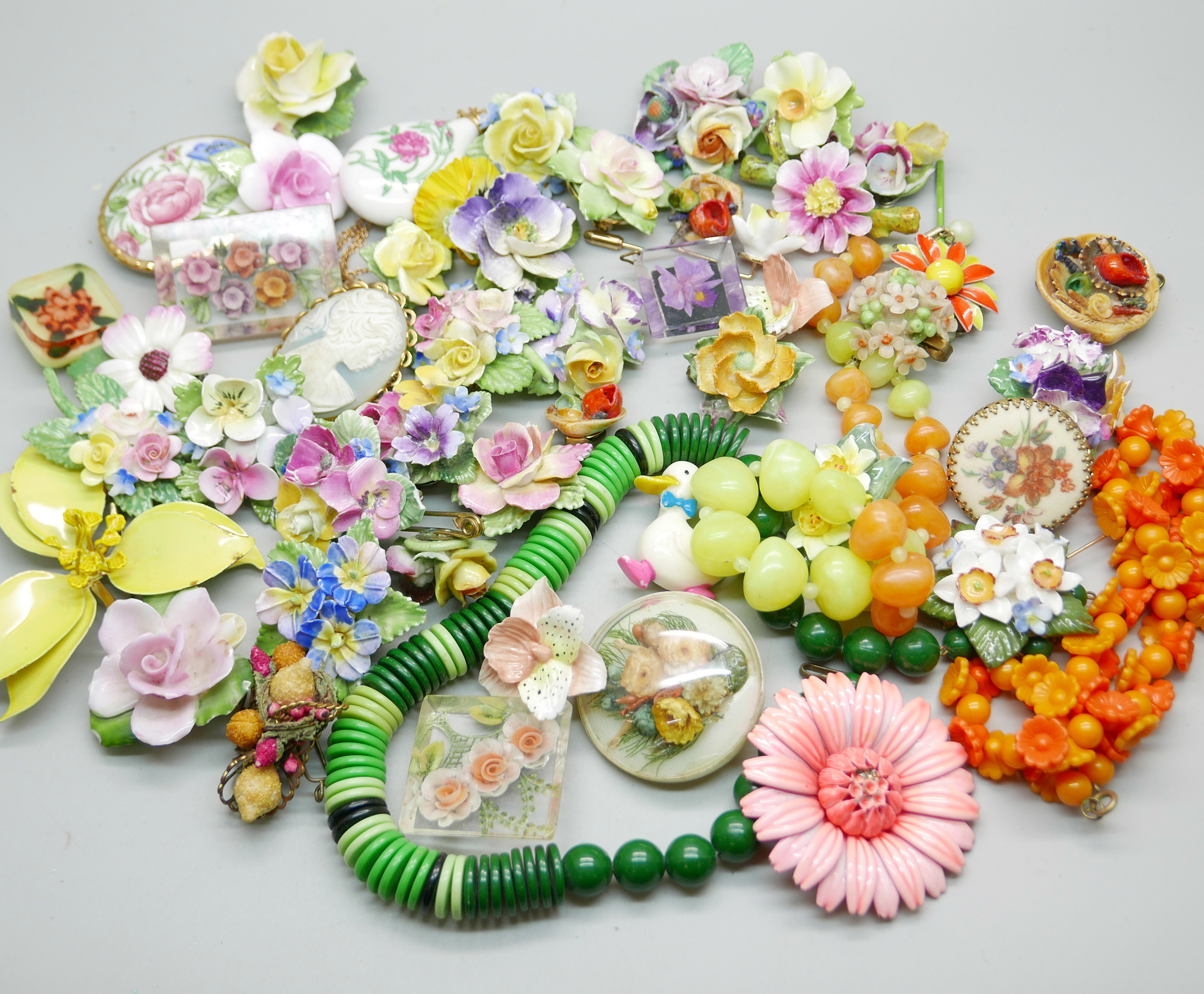 A collection of floral themed jewellery, a pink enameled flower brooch, five celluloid pieces, three