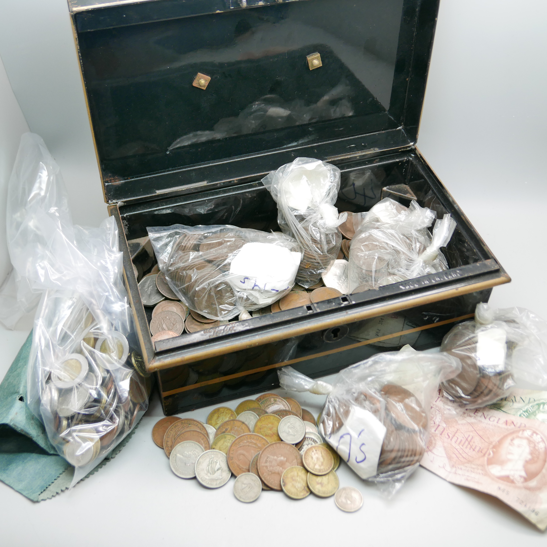 A tin box with a collection of foreign and English coins and notes