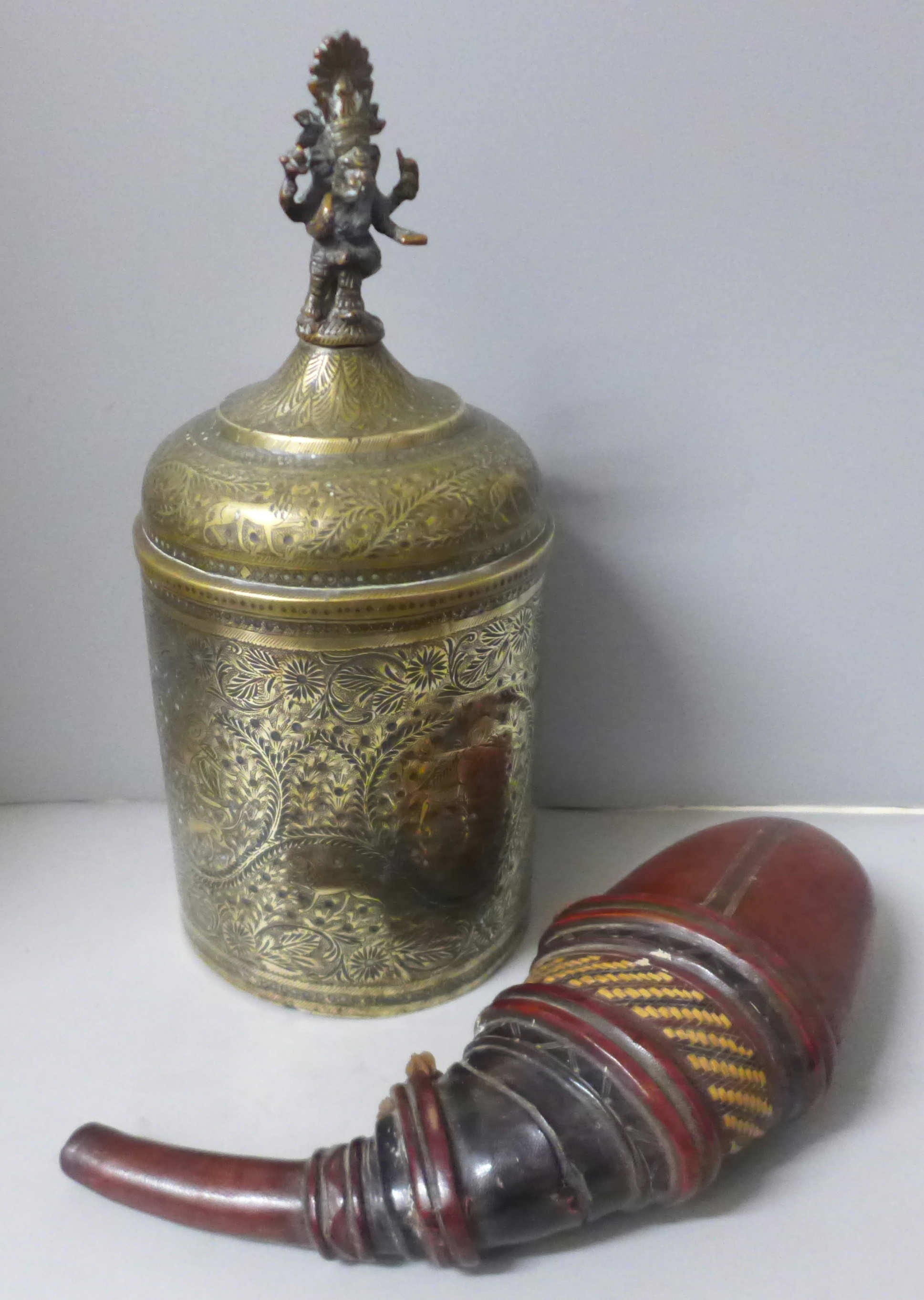 A chase engraved brass Indian lidded caddy with Ganesha top detail, 33cm and a leather powder case